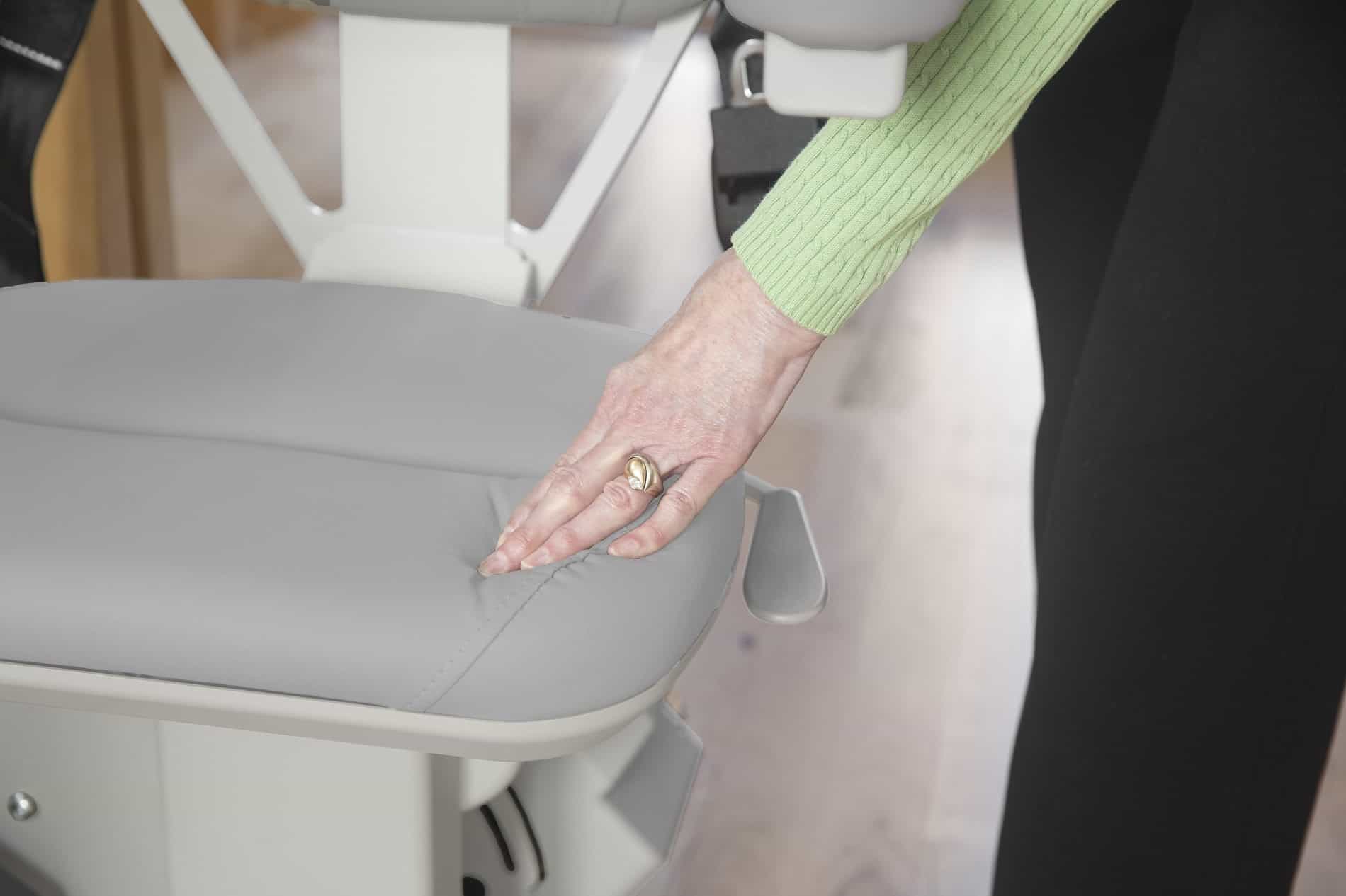 woman standing behind stairlift chair with her hand on the seat