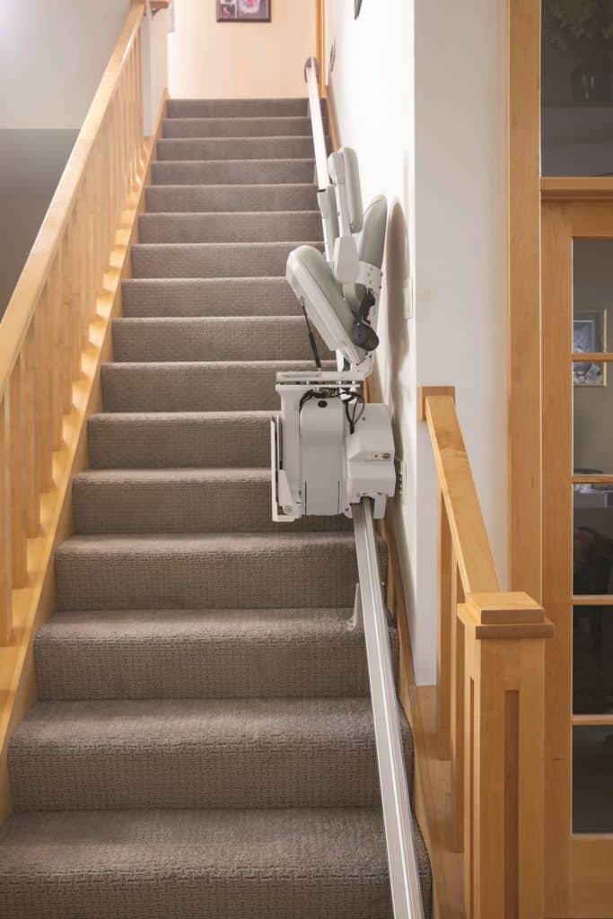full carpeted stairway with stairlift installed against wall on the right