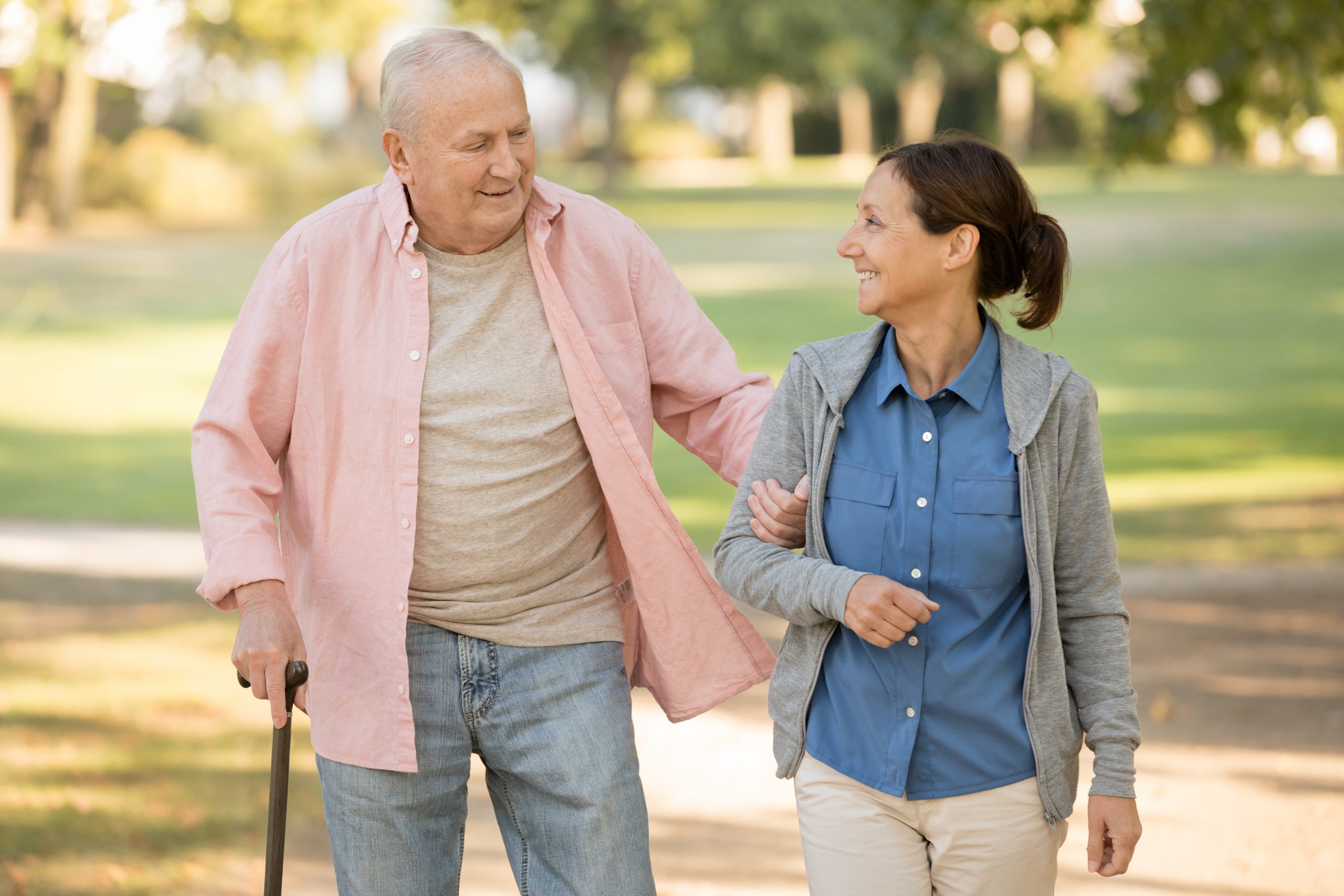 senior man walking with caregiver