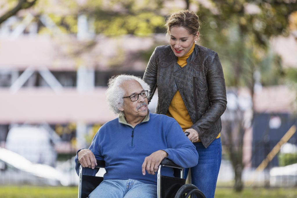 Elderly man in wheelchair with younger woman behind