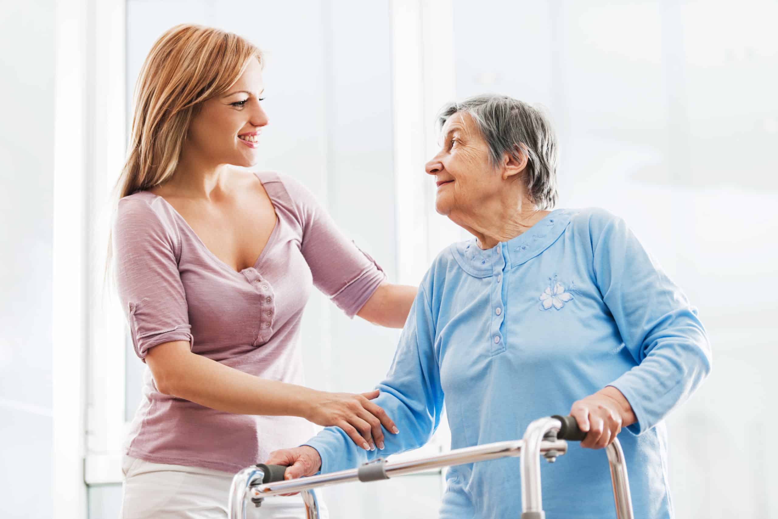 Elderly woman with walker speaking to aide