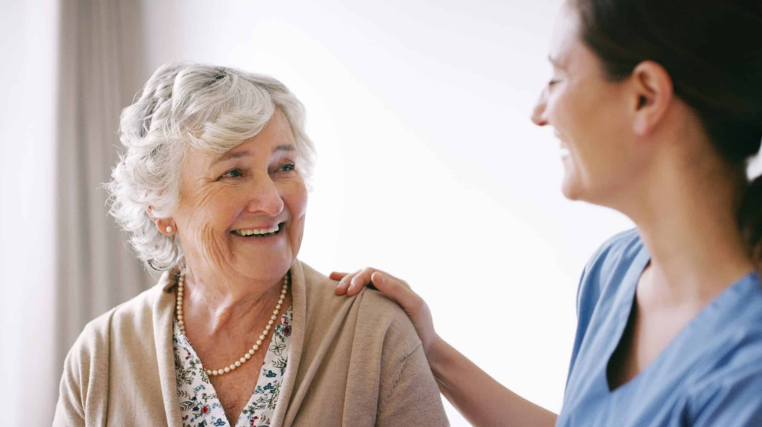 elderly woman smiling while with female caregiver