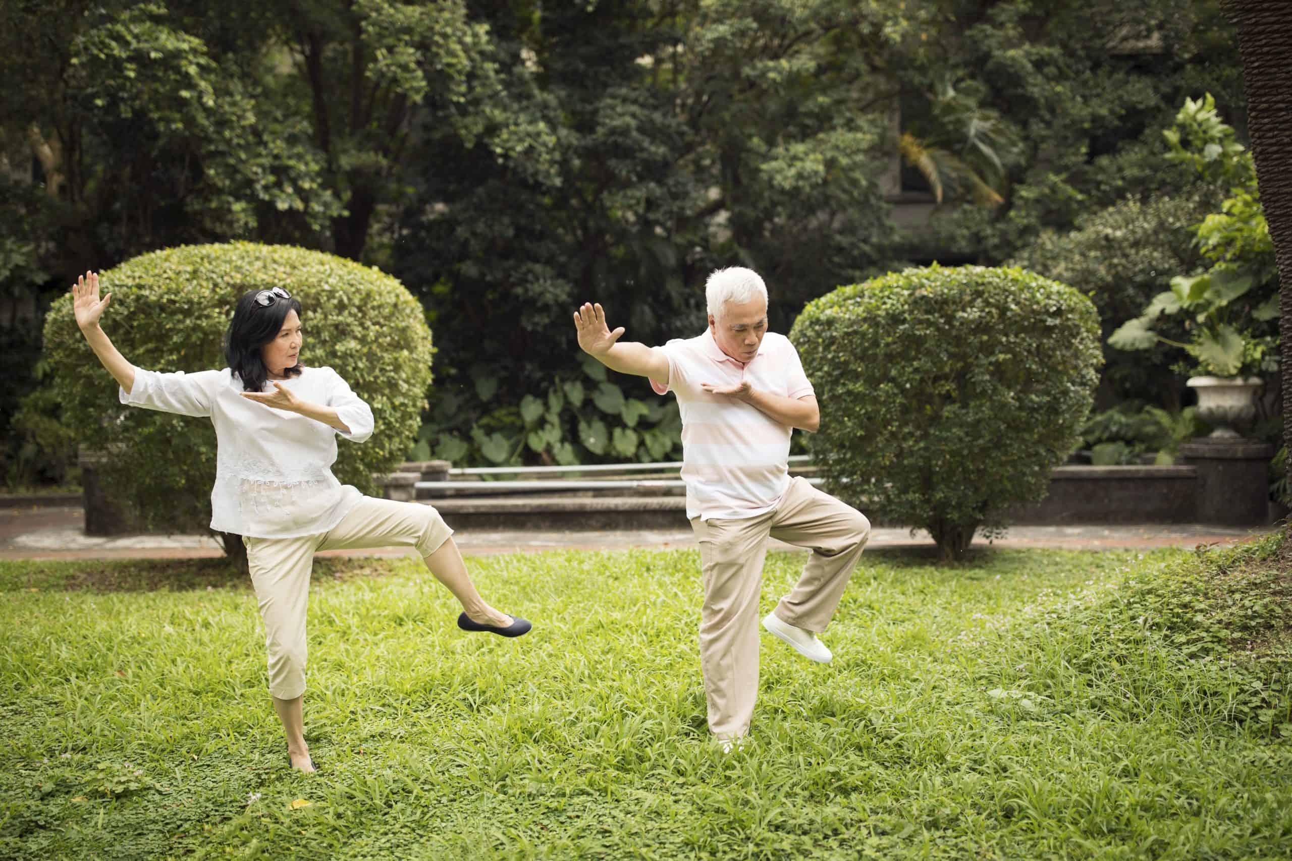 Older gentleman and adult woman practicing Tai-Chi in a park setting