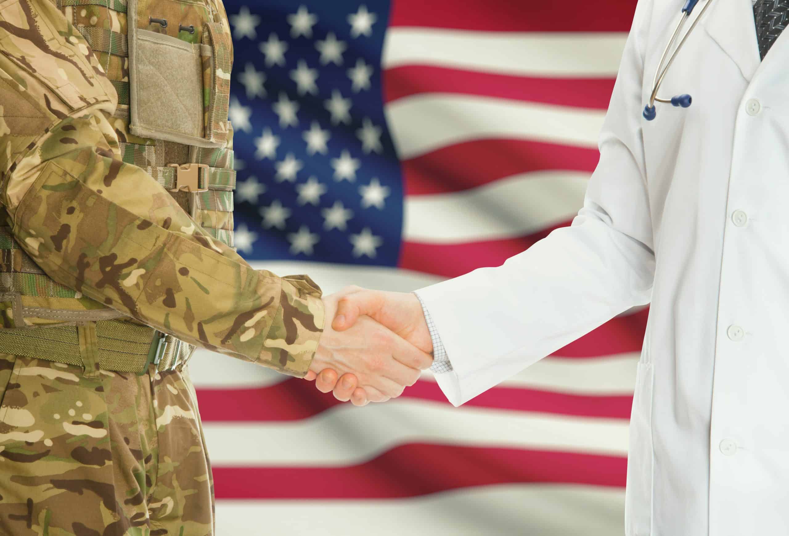 US military personnel shaking hands with medical professional with US flag in background